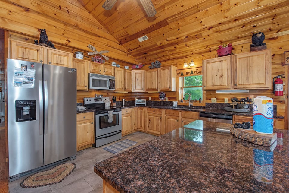 Gather around the spacious granite island in your fully equipped cabin kitchen, where rustic wood beams and modern stainless appliances blend perfectly for your mountain getaway.