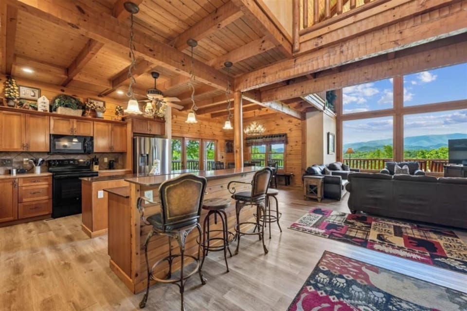 Step into your spacious mountain retreat, where warm wood beams frame stunning views through soaring windows. Gather around the island in your fully-equipped kitchen, then relax in the open living area—all with breathtaking peaks as your backdrop.