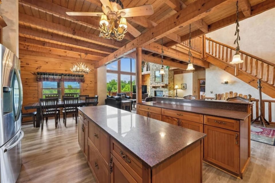 Stunning vaulted ceilings and warm wood beams frame your spacious open living area, where sunlight streams through expansive windows. Your fully-equipped kitchen awaits culinary adventures, while cozy dining and lounging spaces invite memorable gatherings.