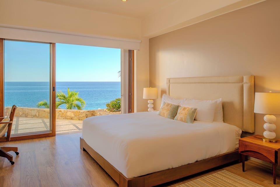 Bedroom 4 · Wake up to breathtaking ocean views from your serene bedroom, where floor-to-ceiling windows frame the endless blue horizon and tropical palms sway just beyond your private terrace.