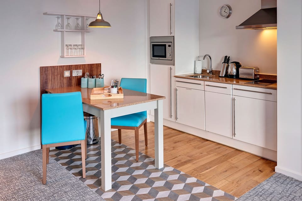 Dining area featuring vibrant blue chairs and a fully equipped kitchen.