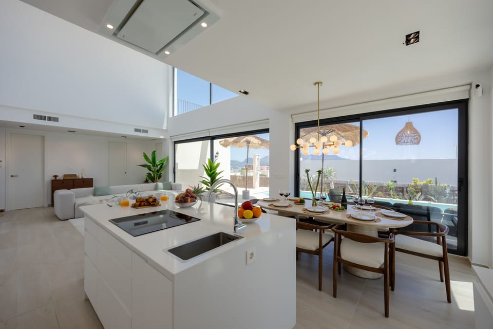 Open-plan kitchen and dining area with island seating and panoramic garden views.