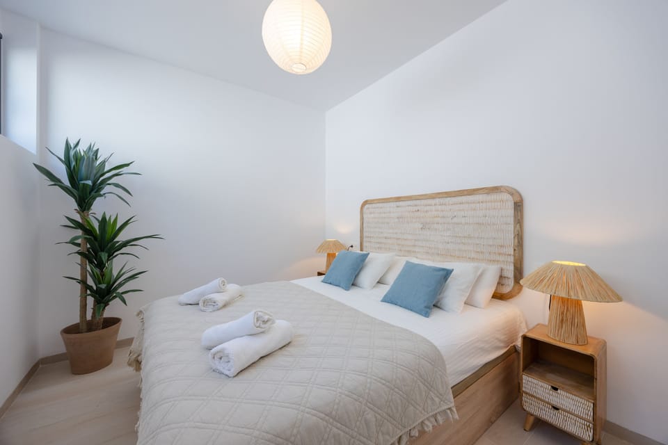 Cozy guest bedroom with a queen bed, natural light, and stylish wicker accents.