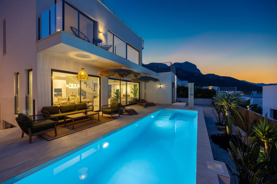 Elegant pool area with sun loungers and stunning mountain views at sunset.