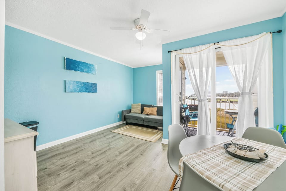 Bright coastal living area with dining nook and balcony water views