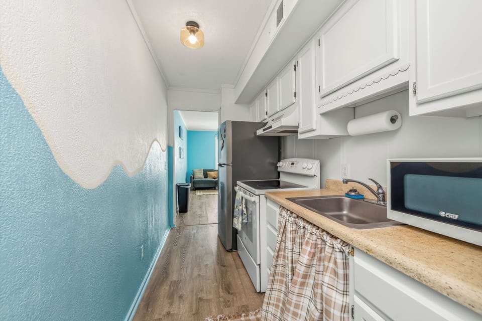 Bright coastal galley kitchen with full appliances and beachy charm