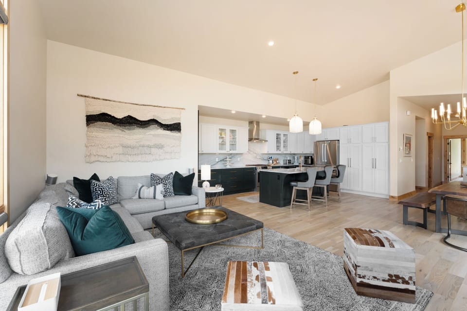 Step into your stylish open-plan retreat where a plush gray sectional invites you to unwind. The modern kitchen flows seamlessly into the living space, perfect for entertaining and creating vacation memories.