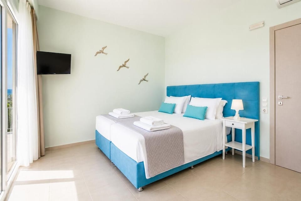 Bright bedroom with turquoise accents, balcony access, and beautiful sea views.