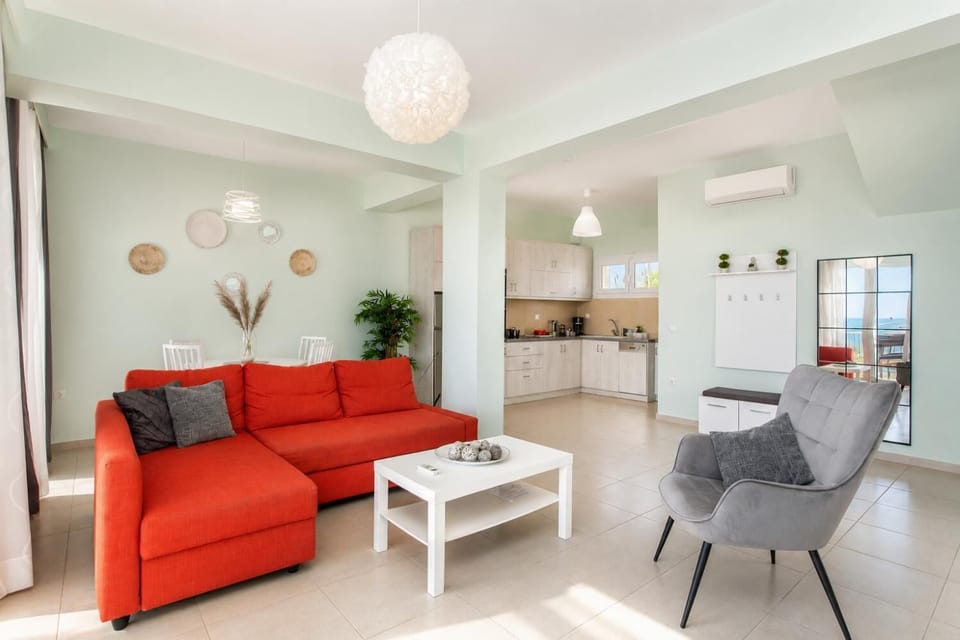 Bright open-plan living area with a comfortable red sofa, modern kitchen, and stylish dining space.