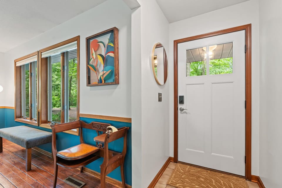 Bright, stylish entryway with forest views and warm wood details