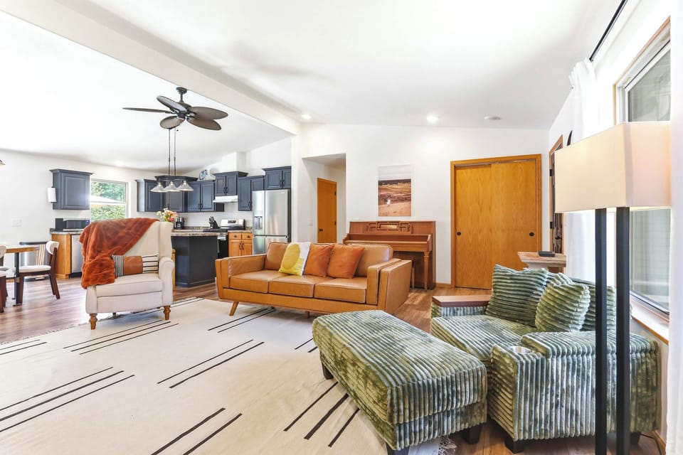 Settle into an airy, open living space where cozy seating, warm textures, and an easy flow to the kitchen make gathering feel effortless.