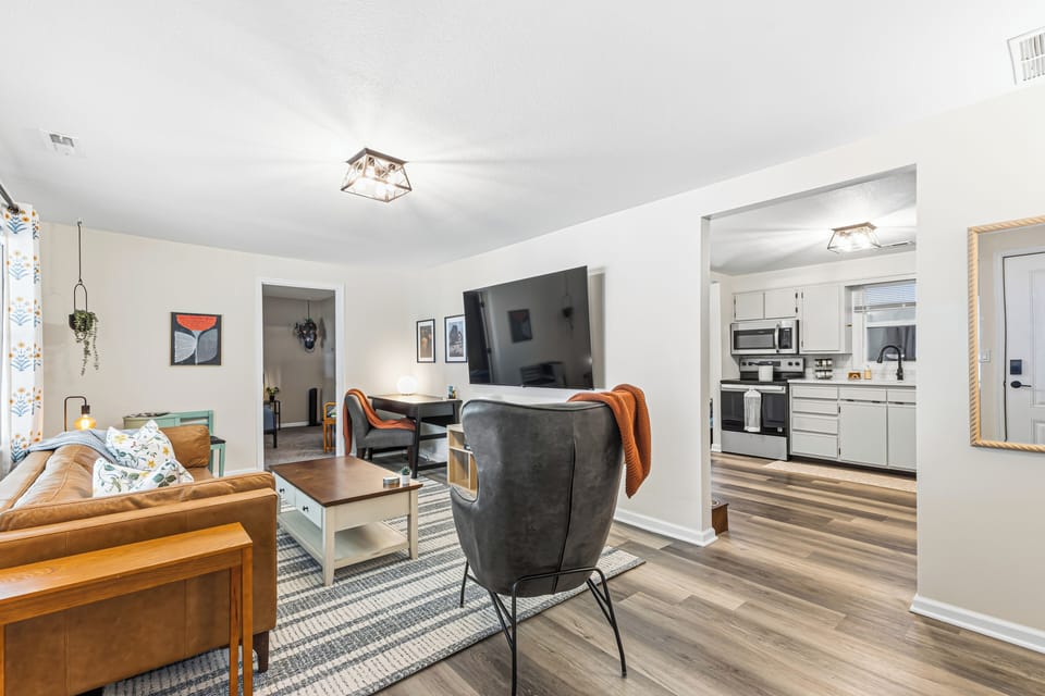 Bright open living room with large TV and modern kitchen access