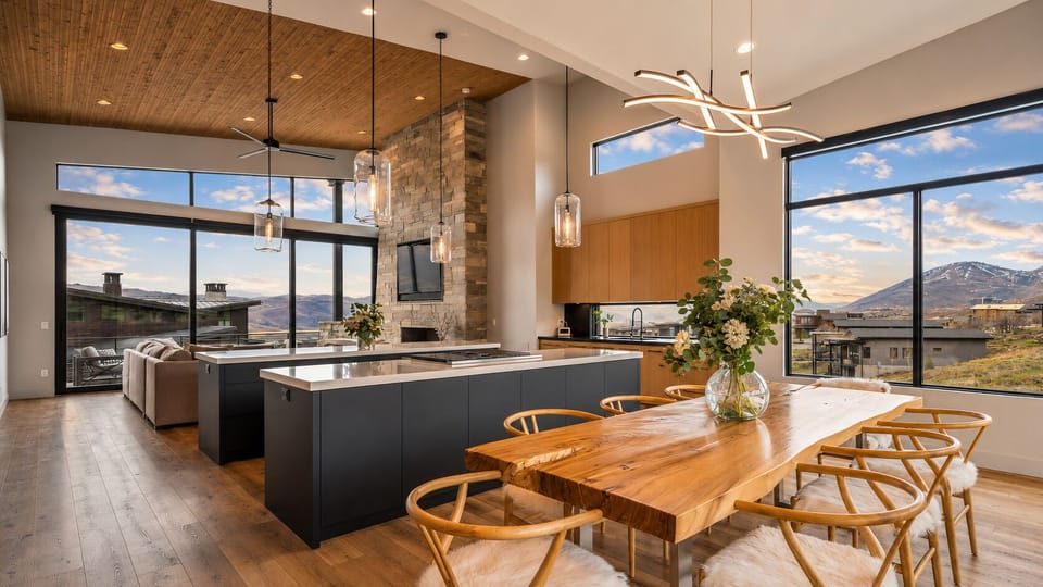 A spacious chef's kitchen flows seamlessly into the dining area, where oversized windows frame breathtaking mountain and lake vistas.