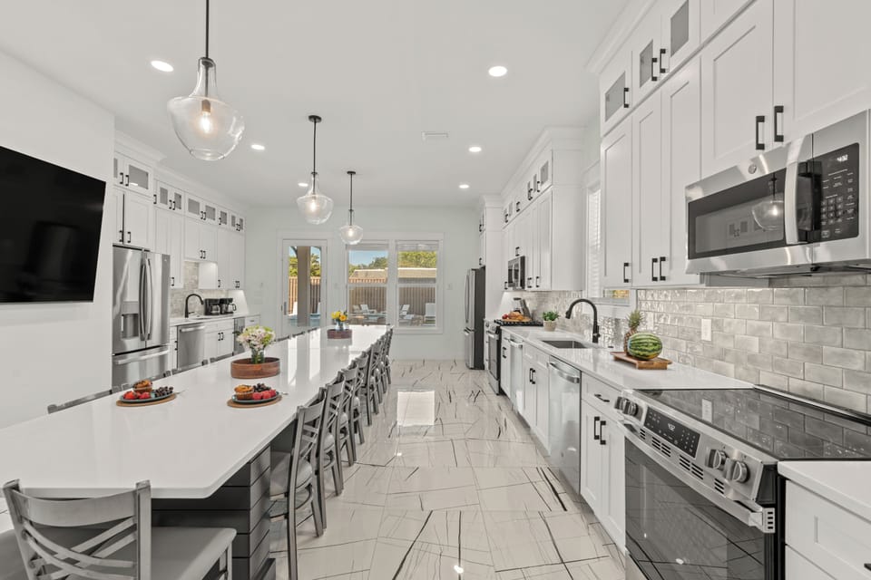 Full perspective of the bright, white cabinetry, high-end stainless steel appliances, and polished flooring.