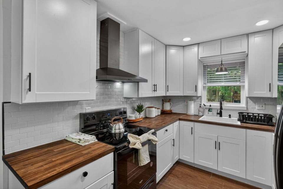 Modern kitchen with white cabinetry, stainless appliances, subway tile, and everything needed for meals.