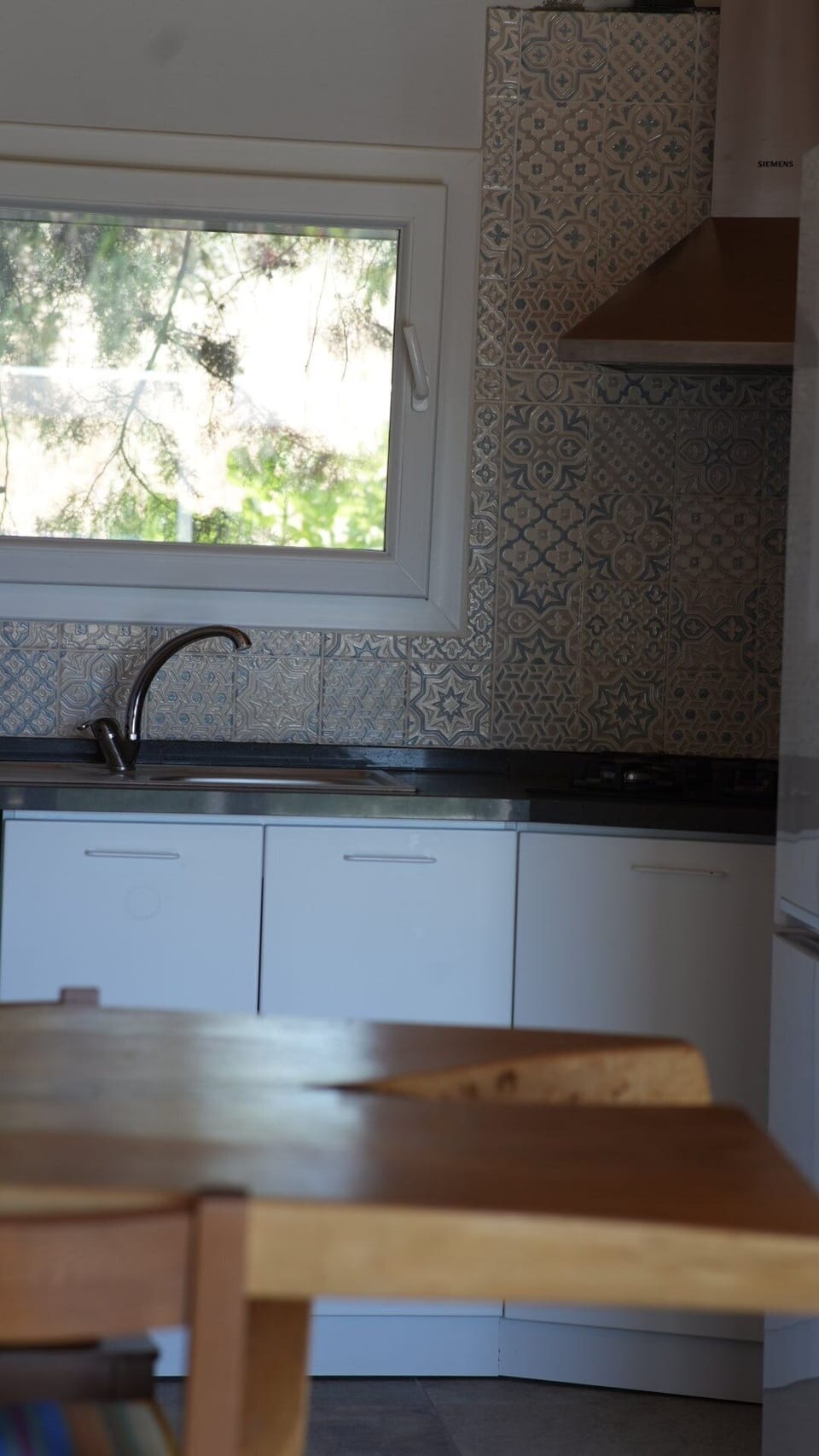 A modern 4-burner gas cooktop surrounded by beautiful patterned backsplash tiles