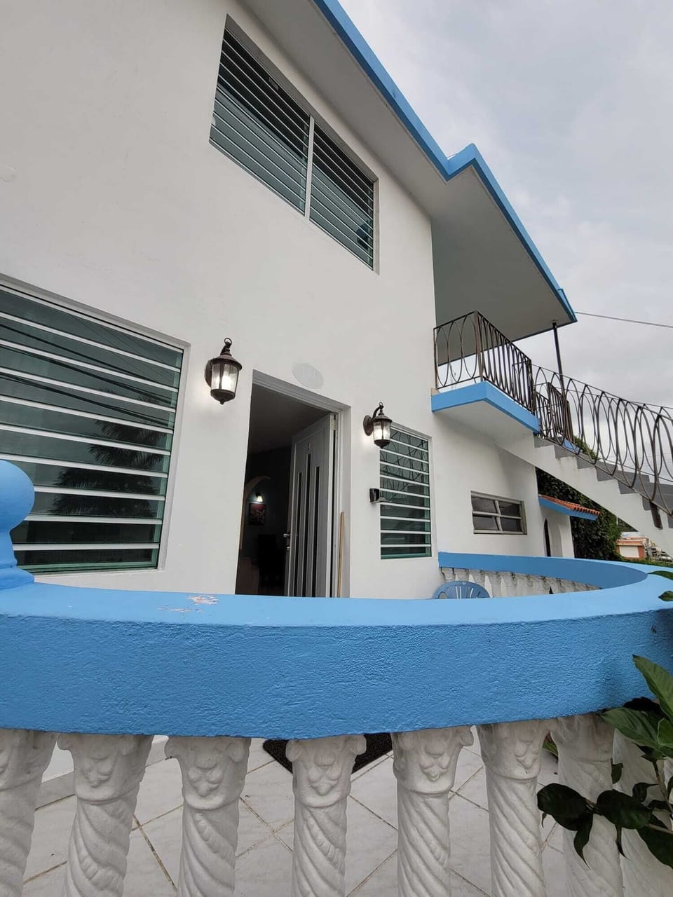 Bright two-story home with balcony, blue accents, and inviting entry