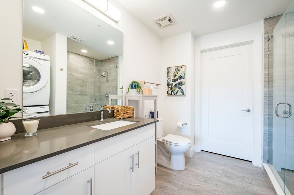 Modern bathroom with vanity, toilet, and walk-in glass shower.