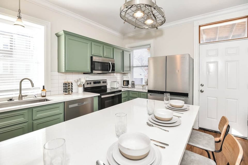 Fully equipped kitchen with island and stainless steel refrigerator.