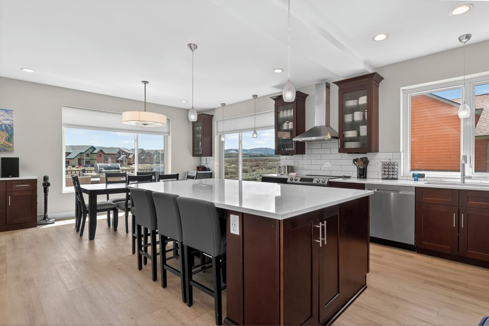 A spacious modern kitchen with a generous island, stainless appliances, and natural light showcasing mountain views beyond the open dining area.