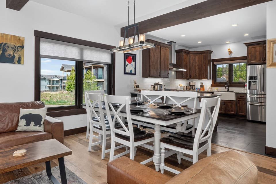 Gather around the farmhouse-style dining table where rustic charm meets mountain elegance. Natural light pours through large windows, illuminating your gourmet kitchen with warm wood tones and stainless appliances ready for your culinary adventures.