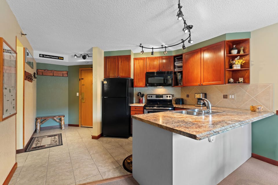 Your fully equipped kitchen features granite countertops, rich wood cabinetry, and modern appliances, perfect for preparing meals during your mountain getaway.