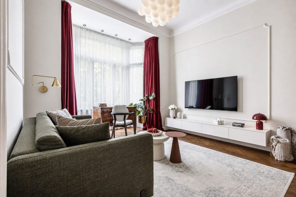 Bright, elegant living room with bay windows, plush seating, and smart TV