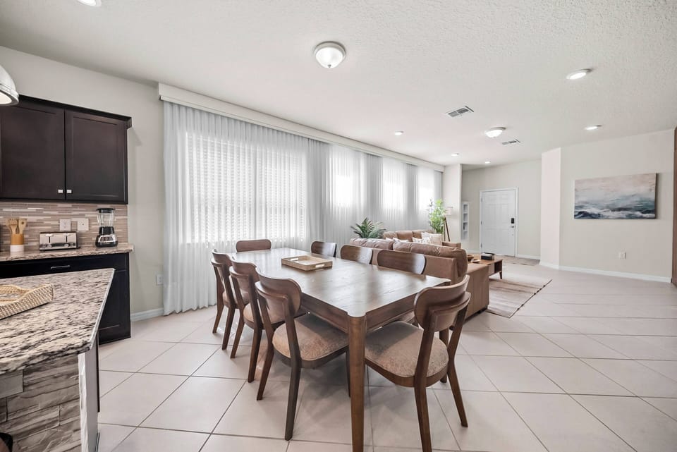 Enjoy the bright, spacious dining area with a sturdy wooden table and stylish chairs perfect for shared meals. The sleek kitchen features rich cabinetry and modern appliances, adding to the warm and inviting atmosphere.