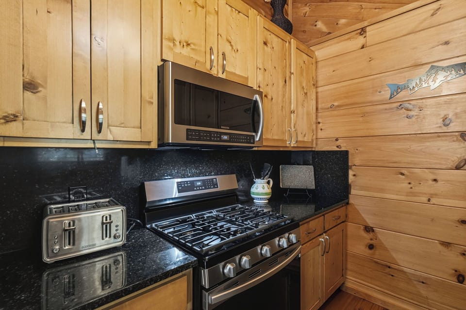 Enjoy home-cooked meals in your fully equipped kitchen with stainless appliances, rich knotty pine cabinets, and elegant granite counters, all set within warm cabin-style walls.