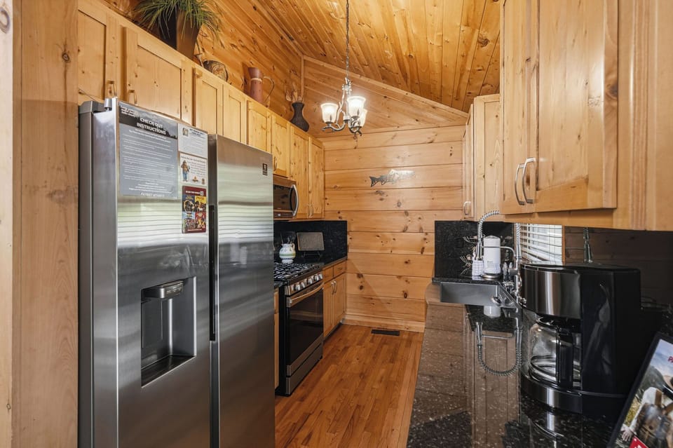 Prepare your favorite meals in this well-equipped kitchen with stainless steel appliances, granite counters, and warm wood cabinetry that sets a cozy, rustic tone for your stay.