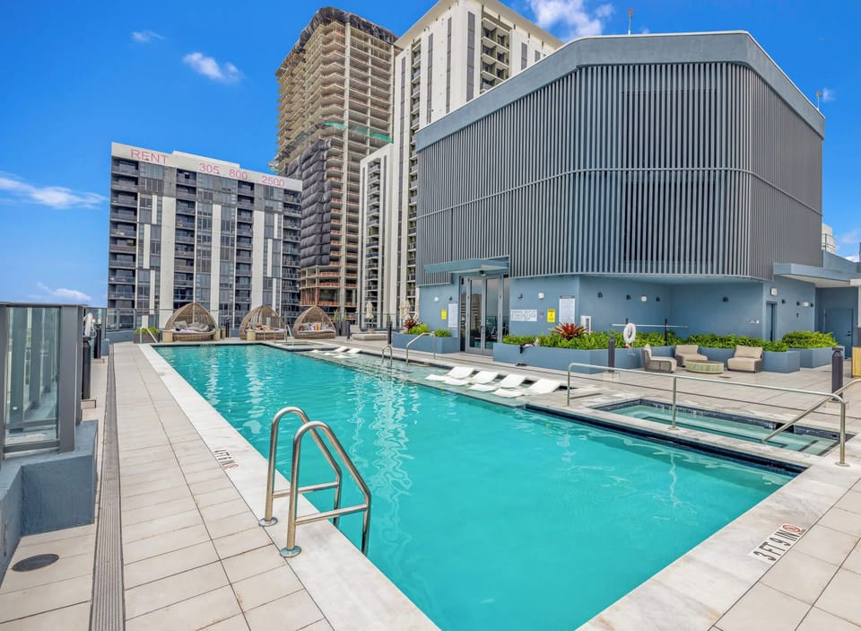 Rooftop pool featuring a lap lane, attached spa, and surrounding high-rise buildings.
