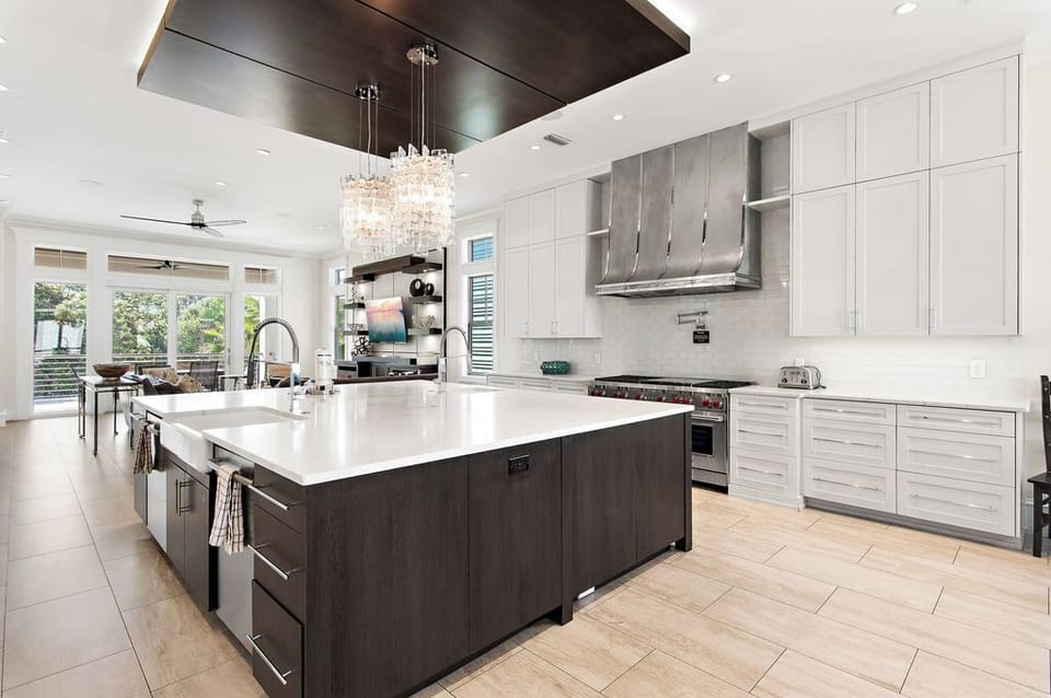 Double-sided kitchen island with marble countertop, dual sinks, and built-in appliances.