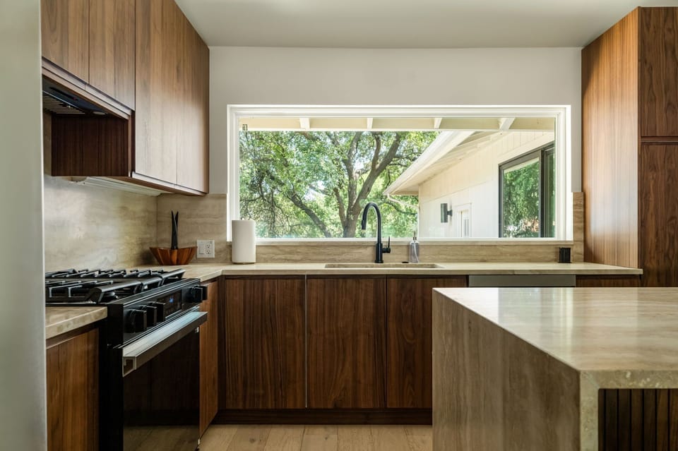 Bright modern kitchen with warm wood finishes and a large scenic window