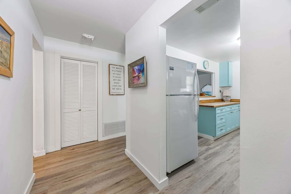 Entryway with wood flooring leading to a kitchen featuring light blue cabinetry and wooden countertops.