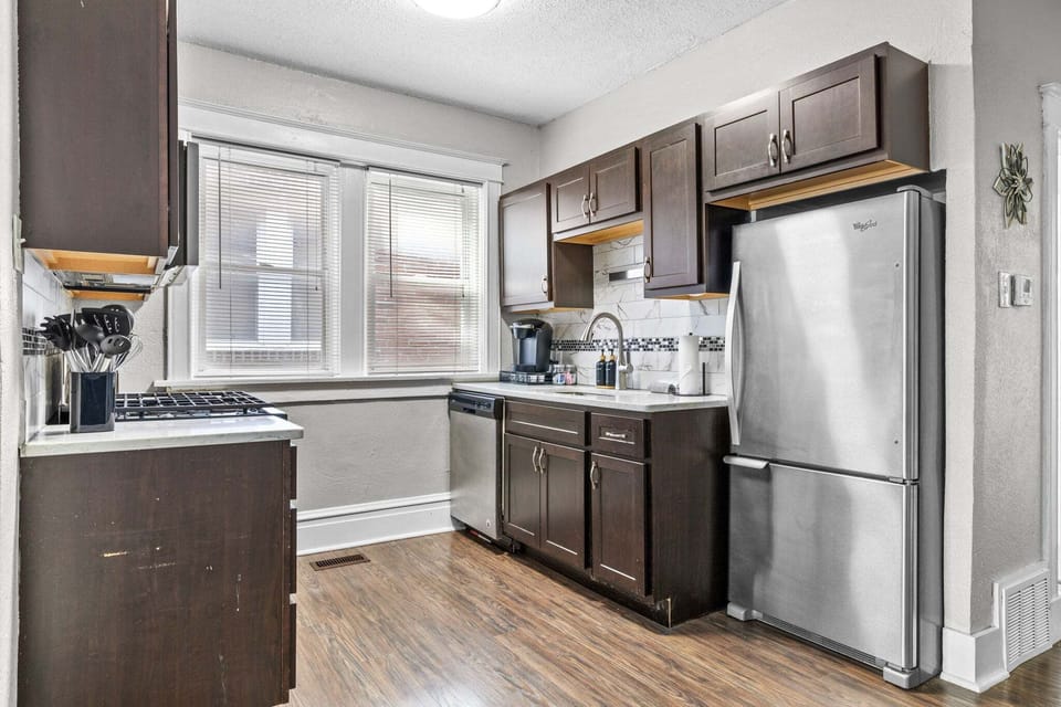 The full kitchen includes a gas range, dishwasher, refrigerator, sink, coffee maker, and dark cabinetry.