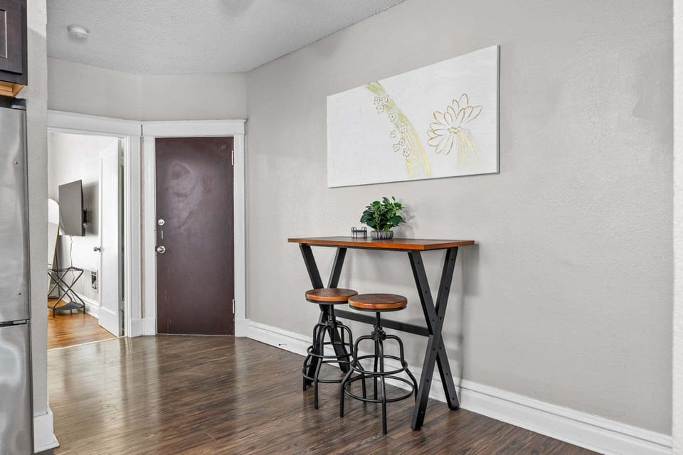 A counter-height table with two stools creates a compact dining or laptop workspace beside the kitchen.
