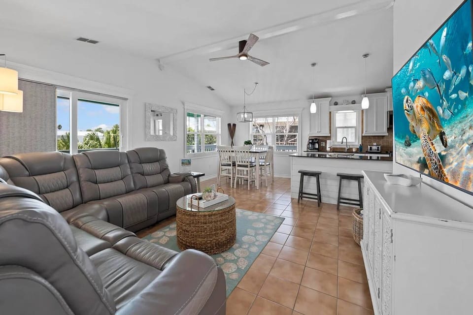 Bright open-concept living, dining, and kitchen space with vaulted ceilings, comfortable seating, and abundant natural light.