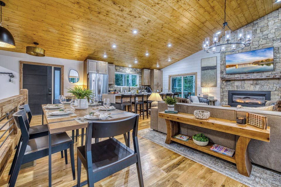 Cozy open-concept great room with stone fireplace and vaulted wood ceilings
