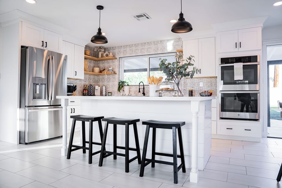 Stunning perspective of the kitchen showing the integration of rustic wood shelving with bright white shaker cabinetry.