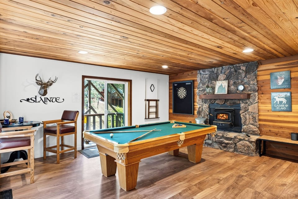 Game room with pool, darts, pub-style seating, and warm cabin character.