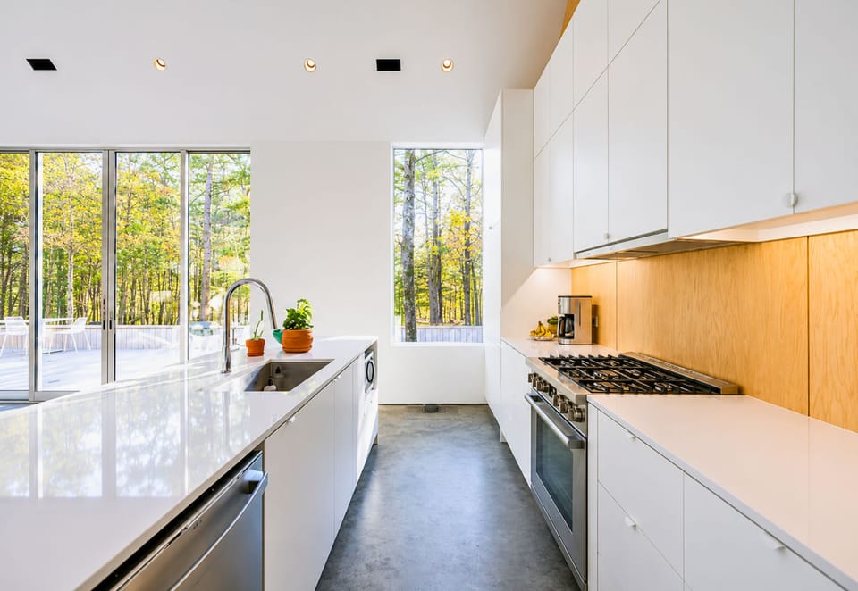 Bright white cabinetry, warm wood accents, and expansive windows make this kitchen feel both modern and welcoming.
