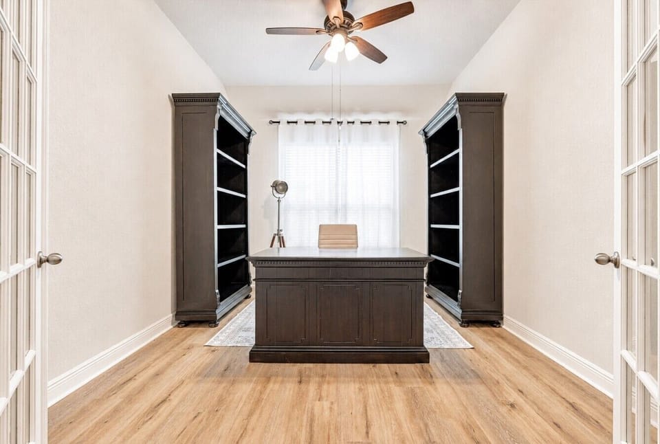Private office with desk, built-in shelving, and French doors.