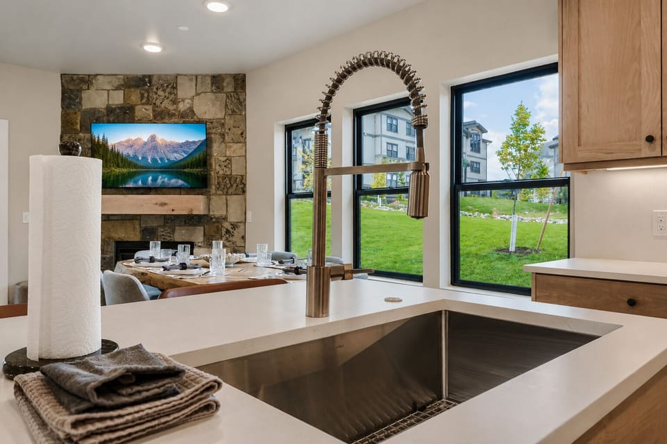 Your open kitchen features modern quartz countertops, a sleek farmhouse sink, and warm wood cabinetry. Prep meals surrounded by mountain views and natural light streaming through the large windows.