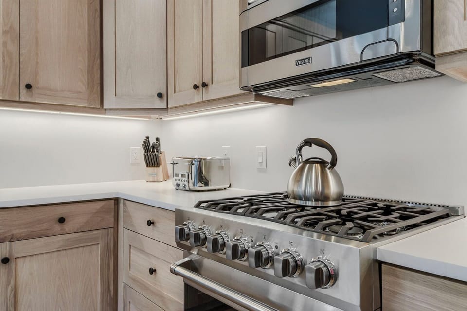 Picture yourself brewing morning coffee in this bright, fully equipped kitchen. The gleaming gas range and modern appliances make meal prep feel effortless.