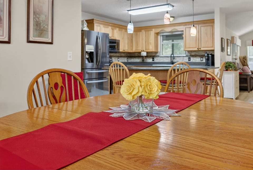 Gather around this inviting dining table where warm wood tones and cheerful yellow blooms create the perfect setting for memorable meals together.