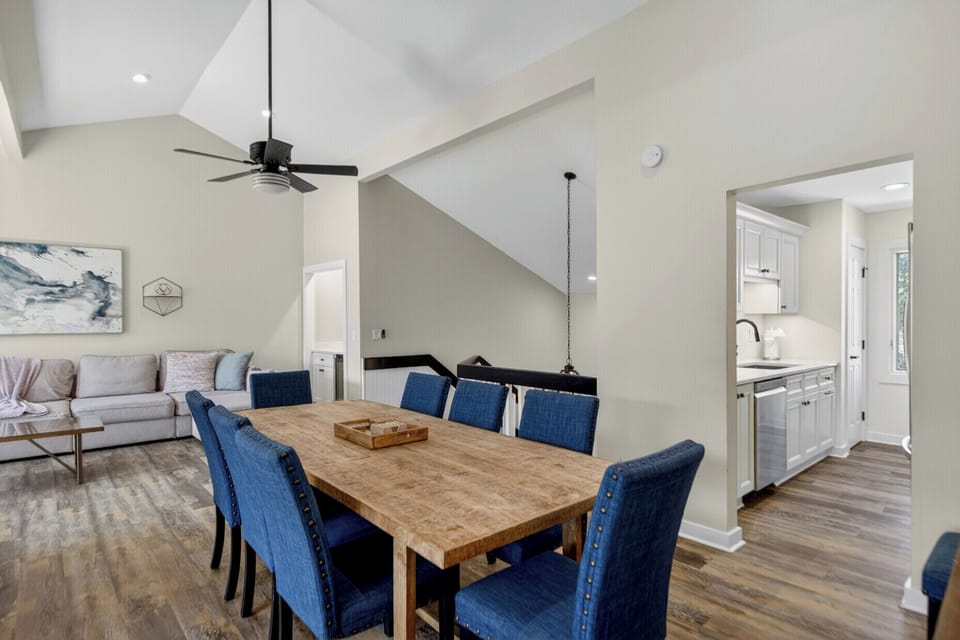 Step into an open, inviting space where your group can gather around this beautiful wooden dining table while meals simmer in the pristine kitchen just beyond. High vaulted ceilings and abundant natural light create a welcoming atmosphere perfect for your 