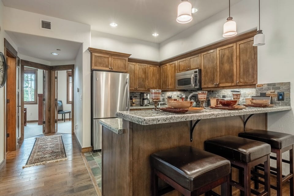 Your stylish kitchen features rich wood cabinetry, granite countertops, and stainless appliances. Gather at the breakfast bar with seating for three and savor morning coffee in this warm, inviting space.