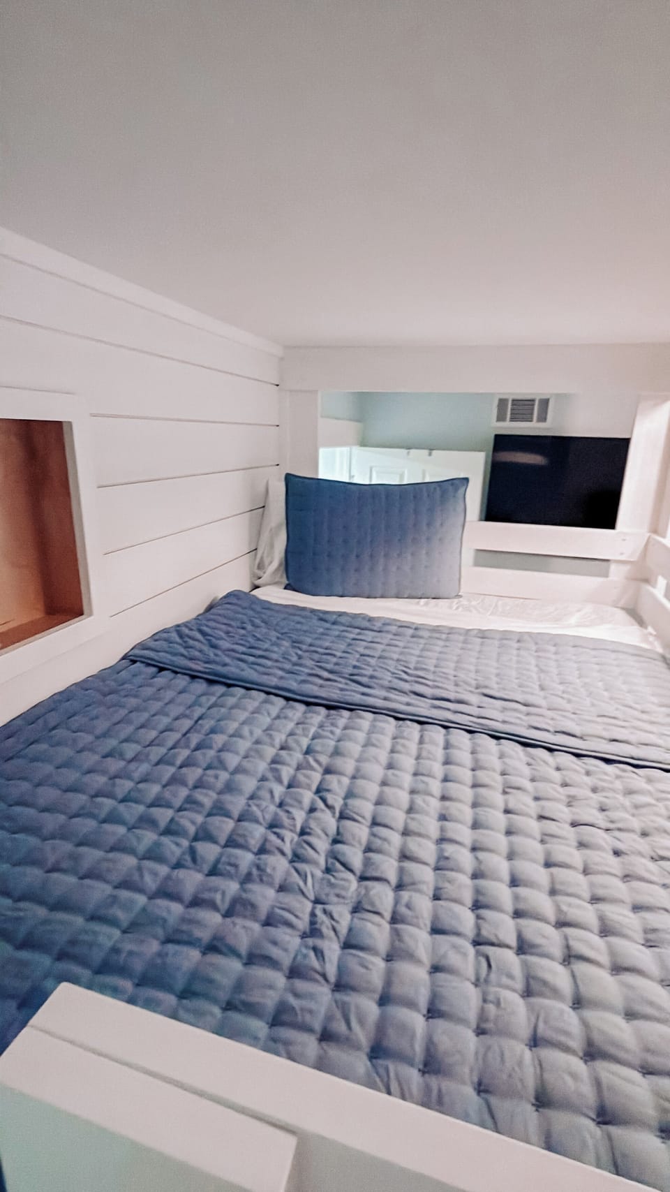 Bunk Room, top bunk detail with cozy navy quilted bedding and powered nook
