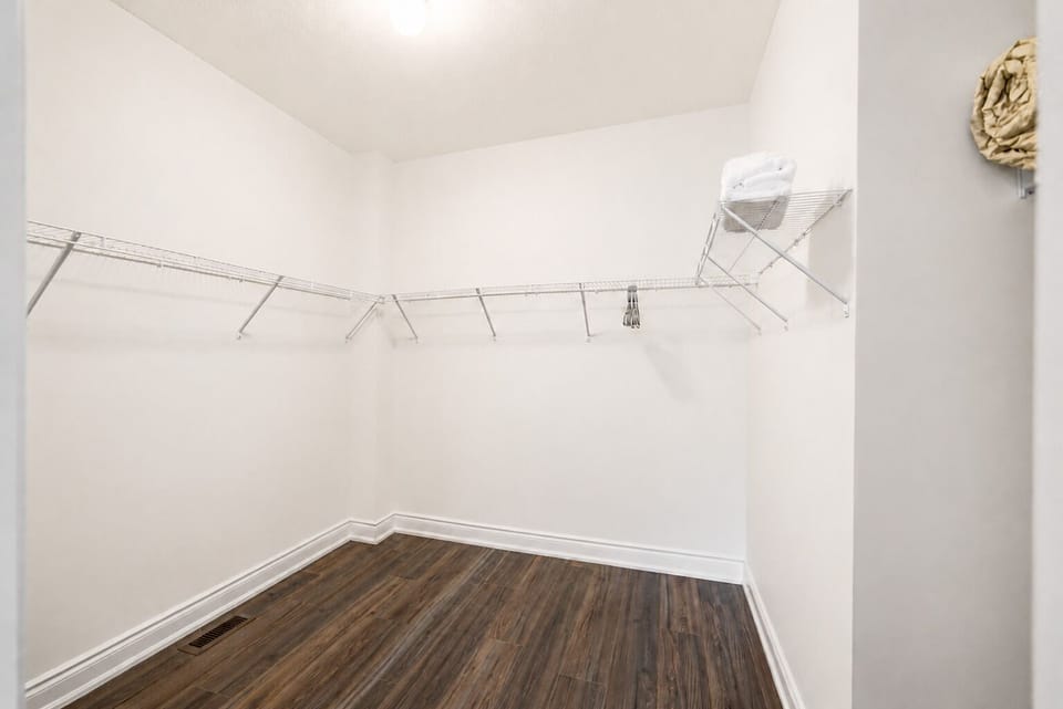 Spacious walk-in closet with ample shelving and stylish wood-look floors