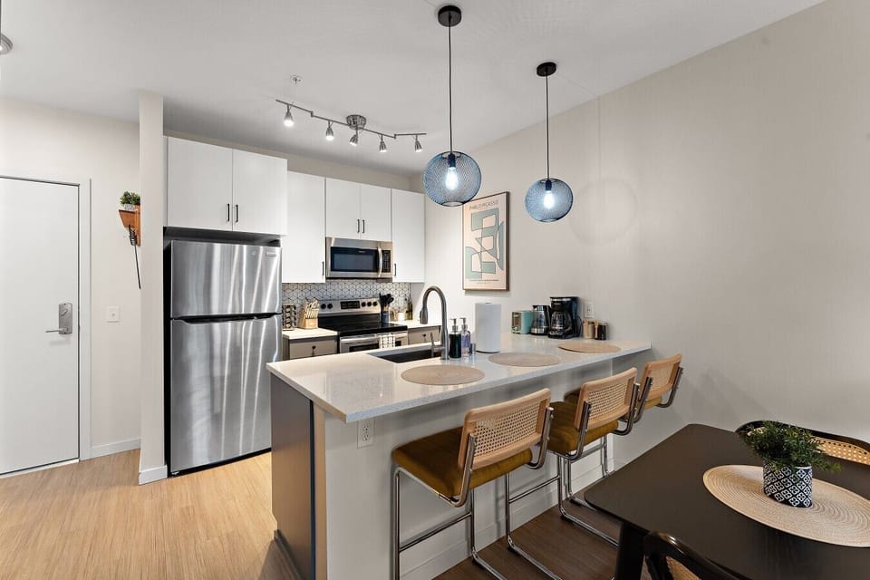 Fully equipped kitchen with stainless steel appliances, bar seating, and an open layout connected to the dining and living area.